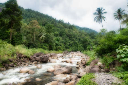 River flowing over rocks through the forest in Kiriwong Thailand
