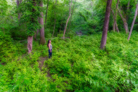 Asian woman standing in forest surrounded by bushes and trees at Chesapeake and Ohio Canal
