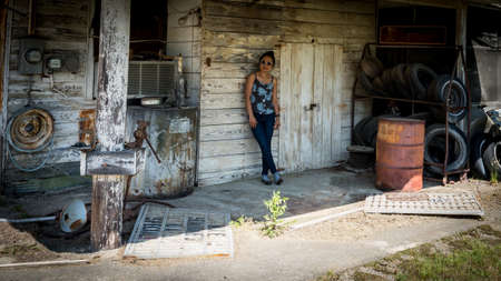 Woman in sun glasses standing and leaning against wall in abandoned gas station