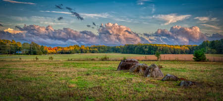 Boulders in a row in a field with storm clouds in the background in Orange County North Carolinaの写真素材