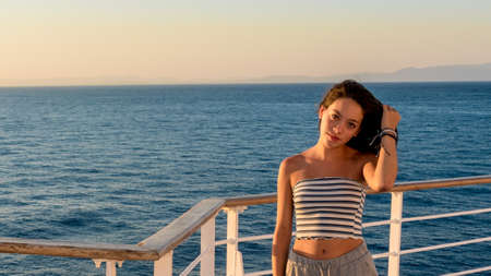 Teen girl in shorts on deck of ferry boat holding hair on ferry boat in Greece