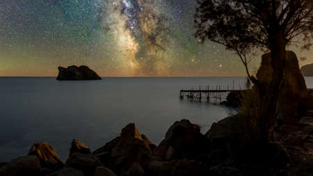 dilapidated,  rundown pier with island in the background on a starry night in Erresos, Lesvos,...