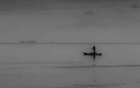Older man fishing on smal traditional boat in calm seas on the Gulf of Thailandの写真素材