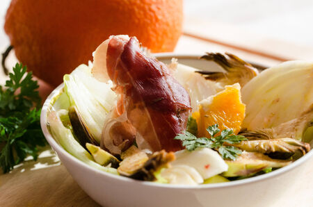 a fresh salad with orange speck artichokes and parsleyの写真素材