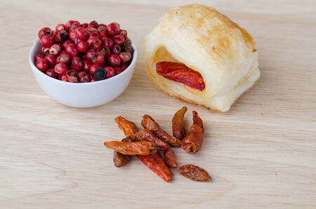 some red pepper grains in a white cup with dried chillies and pretzelの写真素材