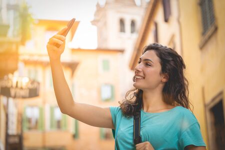 Tourist girl on vacation in Verona taking a selfie on a typical streetの写真素材