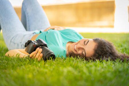 Photographer girl lying on the grass happy and smiling, relaxingの写真素材