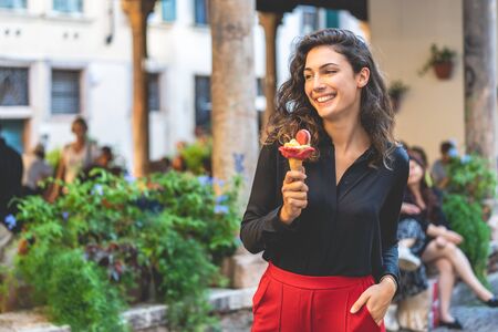 Smiling tourist girl walking with ice cream for a city, holidayの写真素材
