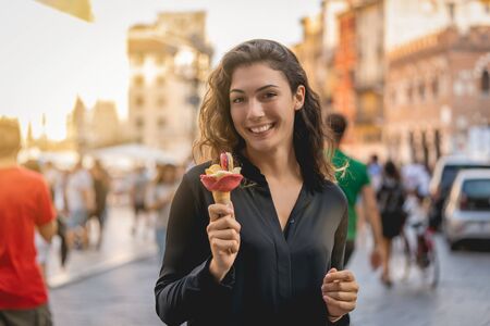 Smiling girl strolling with an ice cream in hand with background of porches, caucasian