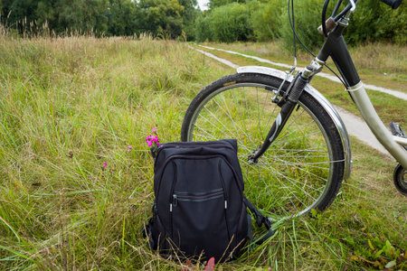 Bicycle and backpack of a tourist near a meadow road.の写真素材