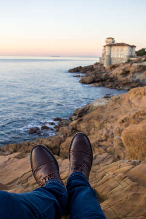 Man relaxing by the sea, sitting on the rocksの写真素材
