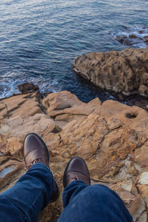 Man relaxing by the sea, sitting on the rocksの写真素材