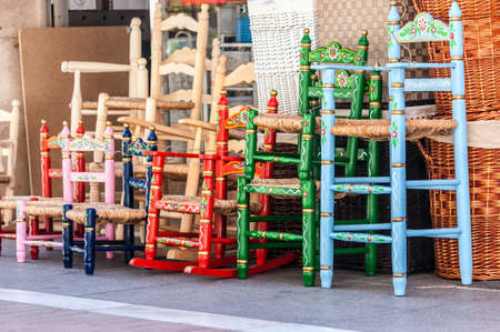 Several wood and wicker chairs in blue, green, red and pink. They are painted floral motifs Withの写真素材