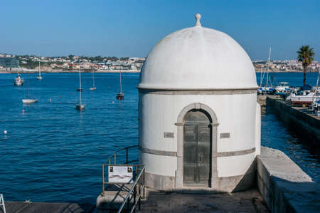 View with sun of the Cascais tide gauge in Portugal, in front of the Tagus Riverの写真素材