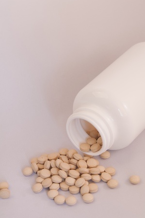 Spilled round pills from white bottle on a clear backgroundの写真素材