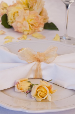 A place setting of white off china with two roses on the plateの写真素材