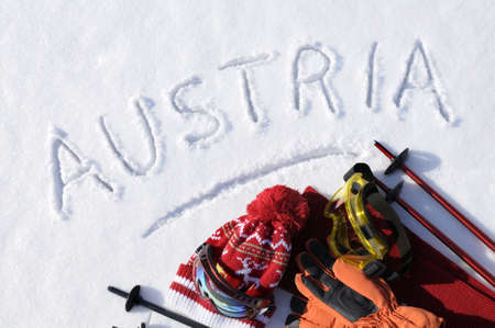 The word Austria written in snow with ski poles, goggles and hats.の写真素材