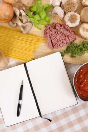 Making Italian spaghetti bolognese with ingredients and blank recipe book or cookbook.  Space for copy.の写真素材