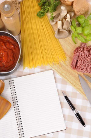 Making Italian spaghetti bolognese with ingredients and blank recipe book or cookbook. Space for copy.の写真素材
