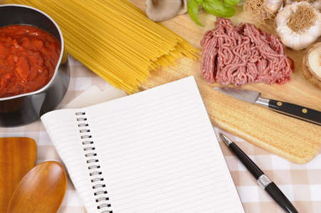 Making Italian spaghetti bolognese with ingredients and blank recipe book or cookbook. Space for copy.の写真素材