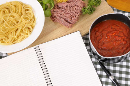 Making Italian spaghetti bolognese with ingredients and blank recipe book or cookbook. Space for copy.の写真素材