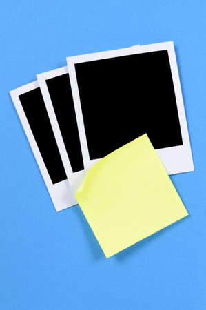 Blank photo prints with yellow sticky note on a blue paper background.
