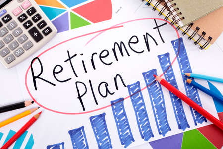 The words Retirement Plan written on a hand drawn bar chart surrounded by pencils, books and calculator.の写真素材
