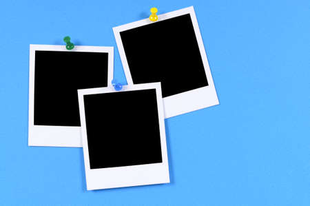 Blank photo prints pinned to blue paper.