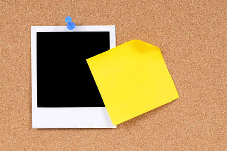 Blank photo print with sticky note pinned to a cork bulletin board.の写真素材