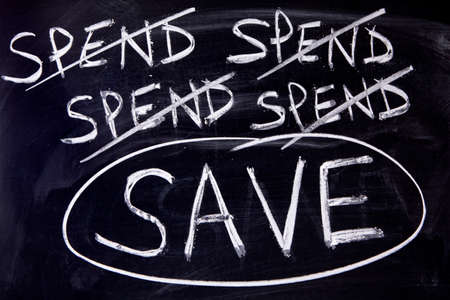 Untidy spend and save message written on a blackboard.の写真素材