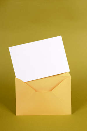 Metallic gold envelope with blank message card letter or invitation isolated on a green background.