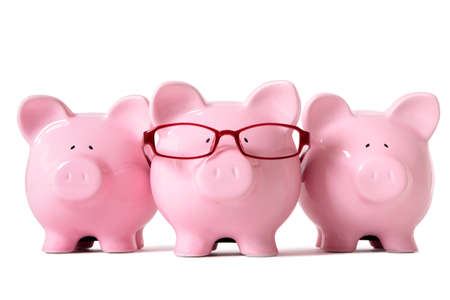 Row of three pink piggy banks, one wearing glasses, isolated on a white background. Sharp focus on middle piggy.の写真素材