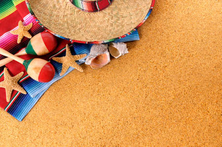 Mexican beach background with sombrero straw hat, traditional serape blanket, starfish, seashells and maracas.  Space for copy.の写真素材