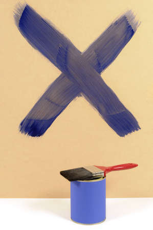 Blue cross or letter X painted on a wood wall with paint can and paintbrush.の写真素材