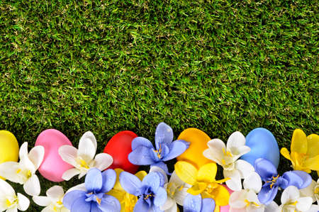 Easter background with hand painted eggs hidden in flowers with copyspace.の写真素材