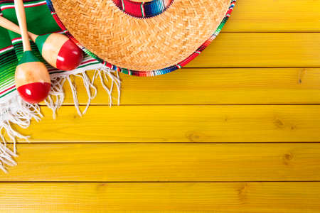Mexican sombrero, maracas and traditional serape blanket laid on a yellow painted pine wood floor.  Space for copy.の写真素材