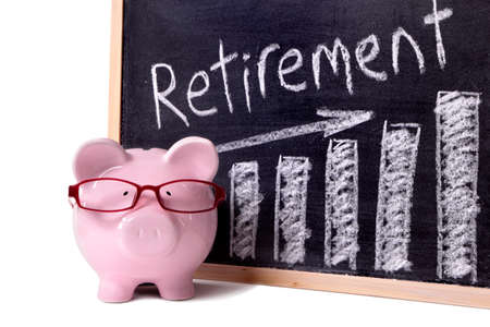 Pink piggy bank with glasses standing next to a blackboard with retirement savings message.  Sharp focus on the piggy bank.の写真素材