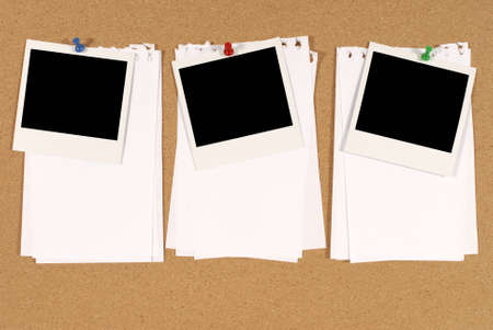 Cork notice or bulletin board with three blank instant camera photo prints and several sheets of untidy torn notepaper. Space for copy.の写真素材