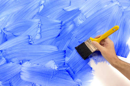 Man holding a paintbrush with a partly finished blank red and white painted wall.  Space for copy.の写真素材