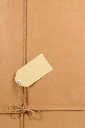 Background of brown paper package with untidy tied label or gift tag.の写真素材