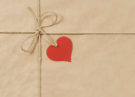 Parcel wrapped in mottled brown paper with coarse rope and red heart tagの写真素材