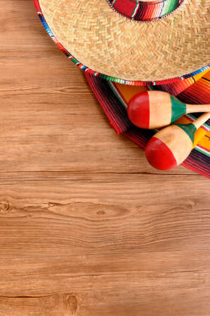 Mexican background with sombrero straw hat, maracas and traditional serape blanket or rug on a wood floor.  Space for copy.の写真素材