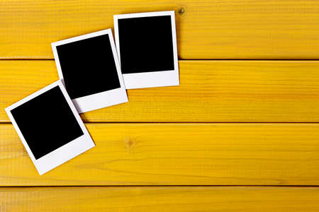 Three blank photo prints on a wood desk or table.  Space for copy.  Paths provided.の写真素材