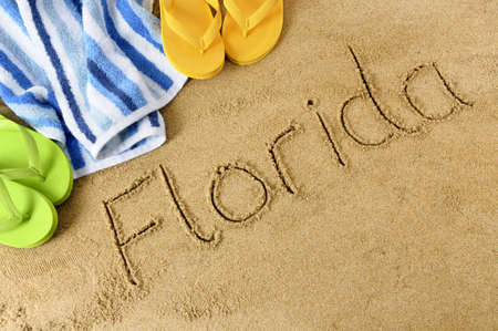 The word Florida written in sand with flip flops and beach towelの写真素材