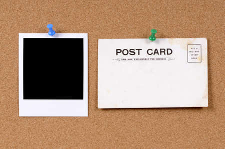 Old stained and faded postcard on a cork bulletin board with blank photo printの写真素材