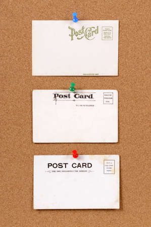 Old stained and faded postcards on a cork bulletin board.の写真素材