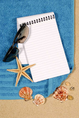 Beach scene with shells, starfish, towel, sunglasses and blank spiral notepadの写真素材