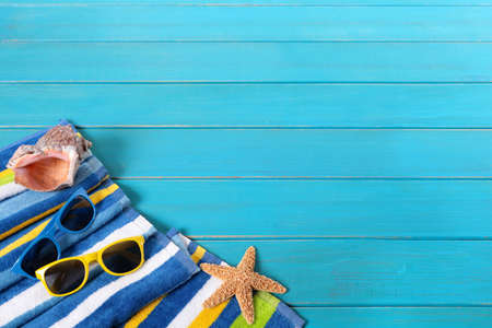 Beach scene with striped towel, sunglasses, starfish and seashell on old weathered blue painted wood...