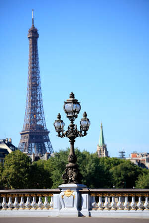 Ornate renaissance street lamp on the famous Pont Alexandre III bridge in central Paris with Eiffel Tower and Paris skyline in the distance.の写真素材