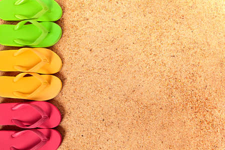 Flip flops in a row, beach sand backgroundの写真素材